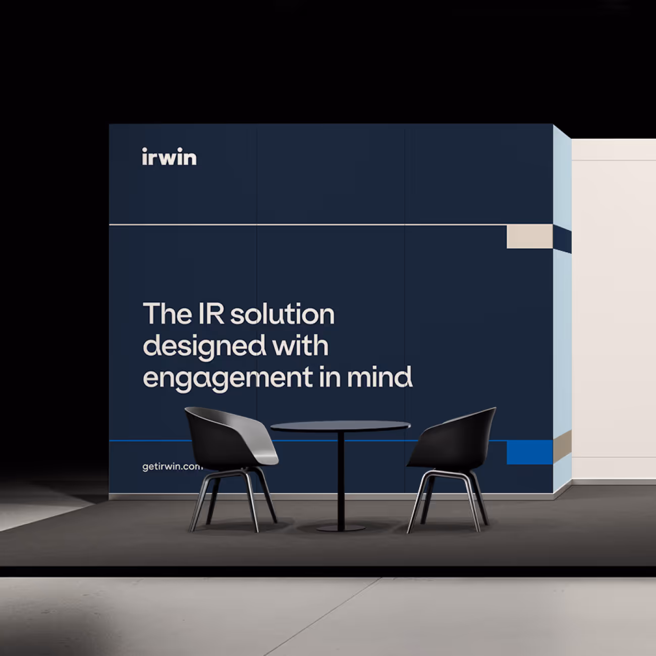 Modern meeting setup with two black chairs and a round table in front of a blue wall with the text 'The IR solution designed with engagement in mind' and the irwin logo.